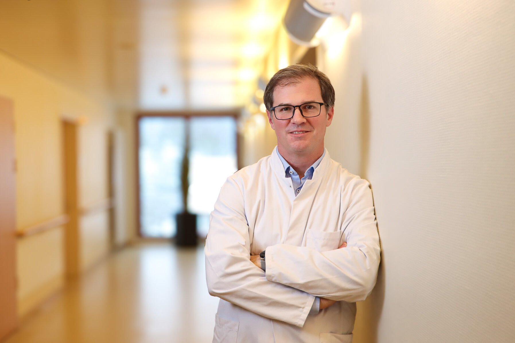 Porträt von PD Dr. Helge Bruns in einem hellen Flur.
